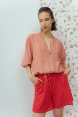 Campera color salmón de corte bomber, con cierre frontal, cuello redondo y ajuste en la cintura con cordones.