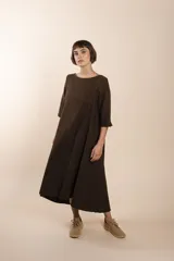 Vestido largo debajo de la rodilla, acampanado, color marrón, con cuello bote, bolsillos en el corte y mangas 3/4.