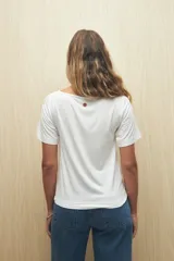 Remera blanca de cuello bote con frunces en los hombros y mangas cortas.