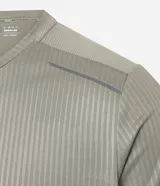 Remera deportiva de manga corta y cuello redondo, color beige claro, con textura acanalada vertical. Presenta detalles reflectantes en los hombros.