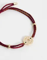Pulsera de cordón ajustable color borgoña con hilo dorado, con dije circular dorado con la inscripción "Lucky Good".