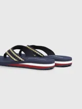 Ojotas Tommy Hilfiger color azul marino con tiras trenzadas en dorado y detalles distintivos de la marca.