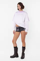 Remera lila con cuello alto y estampado frontal con la frase "Hot and Damaged". Diseño de mangas largas con corte a la altura del codo.