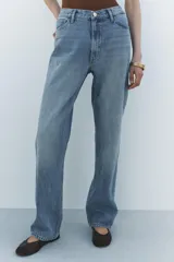 Pantalón de jean celeste de tiro alto, corte recto y largo hasta el tobillo. Tiene cinco bolsillos, trabillas en la cintura, efecto lavado y cierre frontal con cremallera y botón.