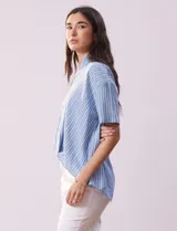 Blusa celeste y blanca a rayas verticales, con cuello con solapa y escote en V. Delantera cruzada con abertura simulada y mangas cortas.
