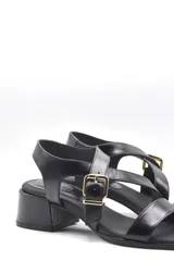 Sandalias negras con tiras cruzadas, hebilla dorada y taco ancho.