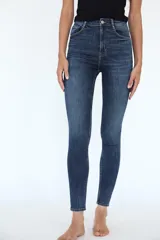 Jeans skinny de tiro alto en denim azul oscuro, con cinco bolsillos y cierre frontal con cremallera y botón metálico.