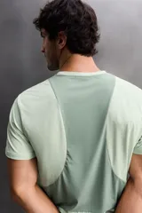 Camiseta deportiva verde claro confeccionada en tejido técnico, ligero y elástico en cuatro direcciones. Tiene cuello redondo, manga corta, zonas con estructura perforada y logo estampado.
