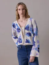 Cárdigan tejido calado color beige con estampado floral en tonos de azul y lila. Escote en V y cierre frontal con lazo.