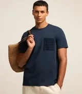 Remera azul marino de algodón, con cuello redondo y manga corta. Presenta un bolsillo delantero con detalles bordados.