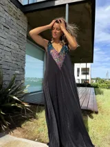 Vestido largo negro con escote en V y breteles finos. Presenta un aplique de lentejuelas multicolores en el escote.