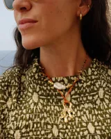 Collar con dije de bronce macizo con forma orgánica o de coral, suspendido de un hilo de seda natural color naranja.