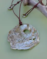 Collar con dije grande de bronce con forma de ostra y cordón de algodón ajustable color gris.