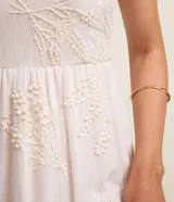 Vestido midi blanco de batista con breteles anchos, escote cuadrado, lastex en la espalda, bordado floral y volado en la pollera.