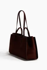 Cartera tote color bordó con doble asa de mano y correas de hombro finas. Cuenta con cierre de mosquetón en el interior y compartimento interior con cierre.