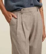 Pantalón wide leg de vestir color beige, con cintura alta, trabillas para cinturón, pliegues frontales y bolsillos laterales.