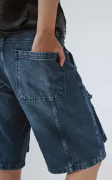 Bermuda de denim azul con efecto lavado, calce oversize y múltiples bolsillos tipo cargo.