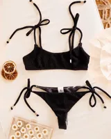 Conjunto de bikini negro con corpiño con tiras finas y bombacha colaless reversible con estampado animal print en blanco y negro.