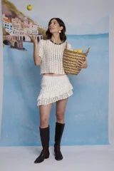 Falda corta color blanco, tejida a crochet, con volados en diagonal.