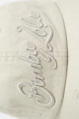 Gorra de algodón color beige con visera curva y bordes desgastados. Presenta bordado frontal con el logo de la marca en color crudo.