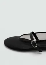Zapato tipo ballerina de malla negra con puntera redondeada y tira con hebilla sobre el empeine.