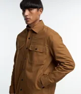 Camisa marrón de manga larga, confeccionada en sarga, con cuello inglés, abotonado delantero, bolsillos en el pecho con solapa y puños abotonados.