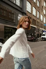Blusa blanca de cuello redondo y manga larga con puños. Presenta bordados florales y entredoses combinados en el frente. Cierre en la espalda con abertura y botón.