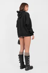 Buzo hoodie negro oversize con bolsillo canguro, cordones ajustables y roturas en terminaciones.