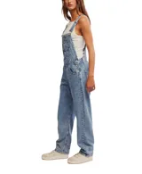 Jardinero de denim azul con silueta holgada, bolsillos delanteros, laterales y traseros, tirantes ajustables con enganche clásico y cierre lateral de botones.
