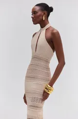 Vestido largo sin mangas color beige, confeccionado en tejido de punto, con cuello alto y calado frontal.