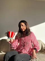 Camisa roja y blanca a cuadros, con cuello alto, mangas largas abullonadas y botones frontales.