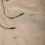 Campera color beige con capucha, cierre frontal con cremallera, bolsillos laterales y puños elásticos.