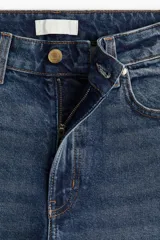 Pantalón jean azul de denim de algodón levemente elástico, corte ancho, tiro alto, largo tobillero y cinco bolsillos.