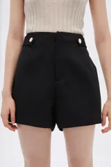 Short negro de poliéster, tiro alto, con bolsillos laterales y cierre frontal con botón y cremallera.