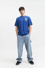 Remera blanca de algodón con cuello redondo y manga corta. Presenta un estampado rectangular en el frente con un diseño abstracto en tonos celeste y azul, y el logo de la marca Mistral.