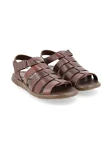Sandalias de cuero marrón con tiras anchas entrecruzadas en el empeine, talón cubierto con ajuste de velcro y suela plana.