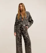 Pantalón largo de corte ancho con estampado paisley en tonos blanco y negro. Presenta cintura alta con trabillas, cierre frontal tradicional y confección en tejido viscolino, una mezcla de lino y viscosa.