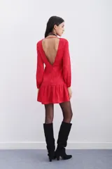 Vestido corto rojo con estampado floral, escote redondo, mangas largas con elástico en los puños, detalle de nudo drapeado en la cintura y escote en V pronunciado en la espalda.