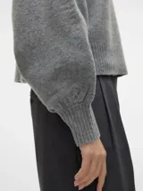 Sweater tejido gris con cuello alto y mangas globo.