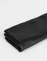 Billetera negra de cuerina con formato fichero, solapa con broche a presión y tag en relieve.