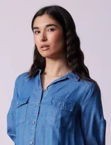 Camisa celeste de lyocell, marca Zac & Rachel. Cuello con solapa, abertura central con botones y bolsillos delanteros.
