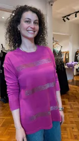 Sweater lila de tejido de punto fino con cuello redondo y mangas largas. Presenta líneas horizontales de strass plateado en el frente.