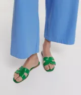 Sandalia plana de cuero sintético color negro, con puntera cuadrada y tiras anchas en forma de H.