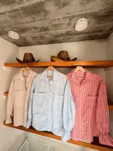 Camisa de organza a rayas verticales rojas y blancas, con mangas largas abullonadas y puños elásticos.