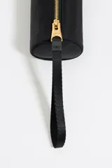 Neceser cilíndrico negro de nylon con asa de tejido y cierre de cremallera, decorado con logo metálico.