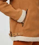 Campera marrón de terciopelo con cuello camisero y forro de sherpa color crema. Tiene cierre frontal con cremallera y bolsillos delanteros con cremallera.