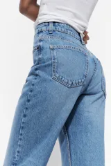 Pantalón de jean celeste de tiro alto, corte recto, con cinco bolsillos y cierre frontal con cremallera y botón metálico.