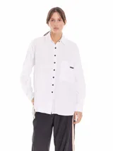 Camisa gris claro de tela Oxford, corte amplio, con cuello clásico, cierre frontal con botones negros, manga larga con puños abotonados, bolsillo de parche en el pecho y ruedo redondeado.