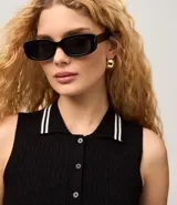 Top de punto sin mangas color negro, ajustado al cuerpo, con cuello polo que presenta ribetes blancos contrastantes. Tiene un cierre frontal de tres botones y un ribete blanco en el ruedo inferior.