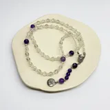Rosario con cuentas de cuarzo cristal transparente y amatista morada, con medalla de San Benito de acero hipoalergénico.